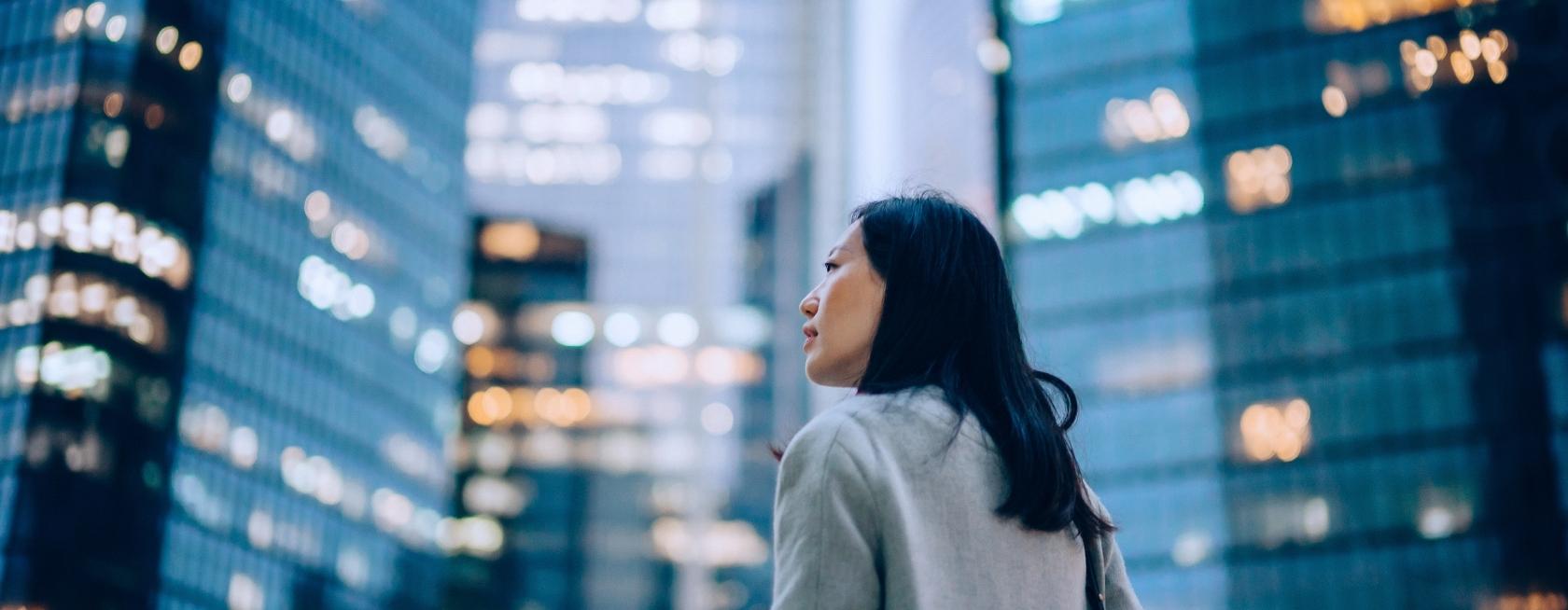 Mujer de pie frente a rascacielos corporativos contemporáneos